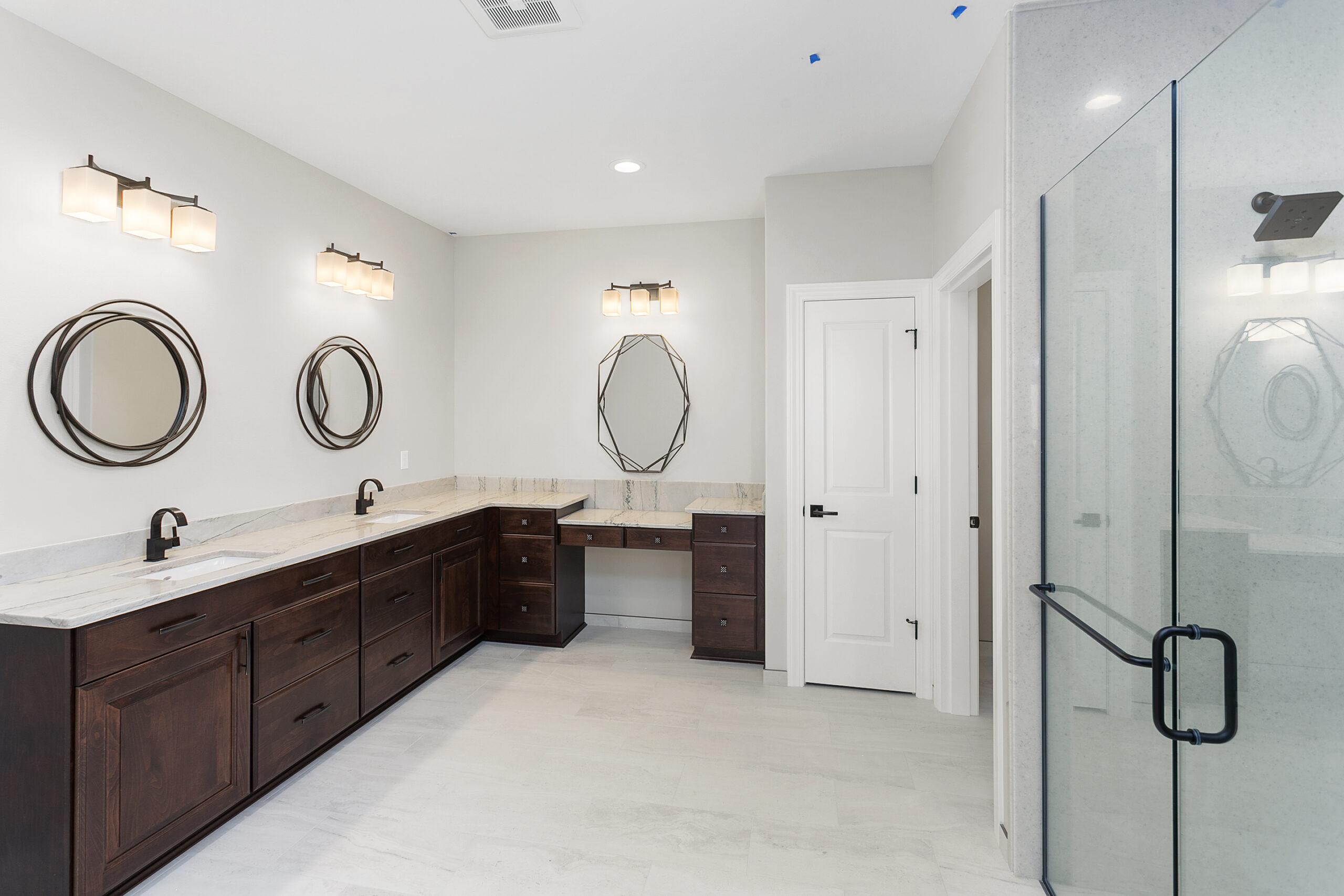 A contemporary modern bathroom design. featuring glass shower stall, and his and her double sink vanity with mirrors.
